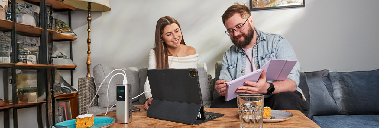 Zdjęcie przedstawiające kobietę i mężczyznę ładujących tablet za pomocą PowerPlay Ultra 140 W